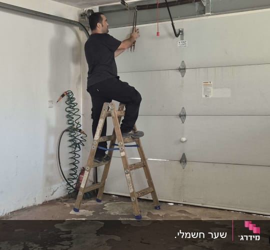 אדם עובד על שער חשמלי עם סולם וכלים